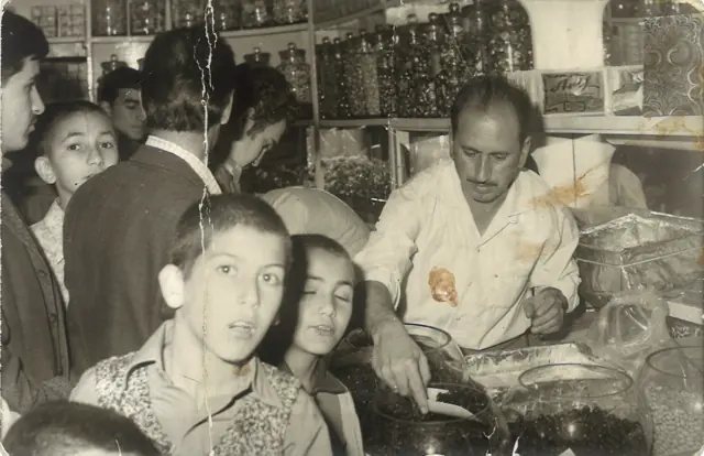 Arif Usta, kalabalık bir bayram gününde tezgâhta müşterileriyle ilgileniyor